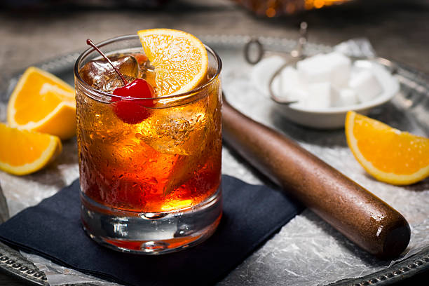 Old Fashioned Cocktail in a Vintage Bar "The Old Fashioned is most commonly made by muddling sugar cubes with bitters, a cherry and an orange wedge or peel. Usually a splash of water or soda water is added along with ice, bourbon (or rye) and a garnish." whiskey photos stock pictures, royalty-free photos & images