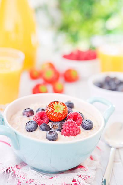 istock Oatmeal porridge with fruit on a rustic table, brightly lit 181880883