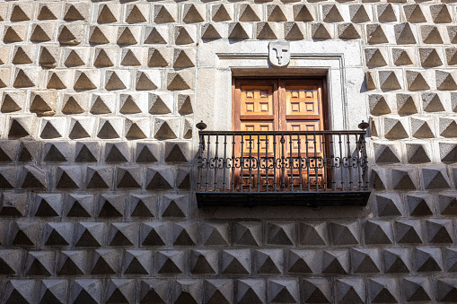 The Casa de los Picos, historic Renaissance building in Segovia, Spain, with characteristic facade of granite blocks carved into pyramid-shaped reliefs and balcony with heraldry of de la Hoz family.
