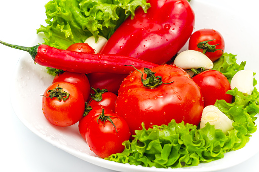 Delicious vegetable salad in bowl with water drops. Tomatoes, lettuce, garlic, chili, sweet pepper