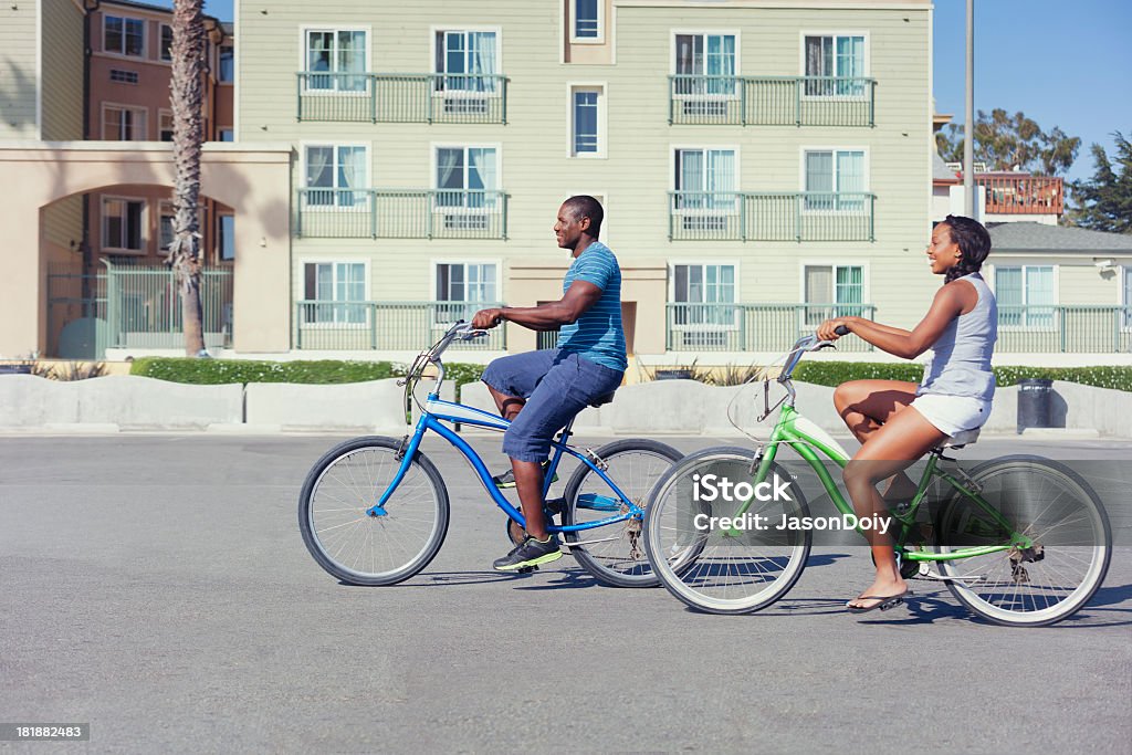 Riding Beachcomber Bicycles A fit athletic couple riding bicycles outside of apartments. Apartment Stock Photo