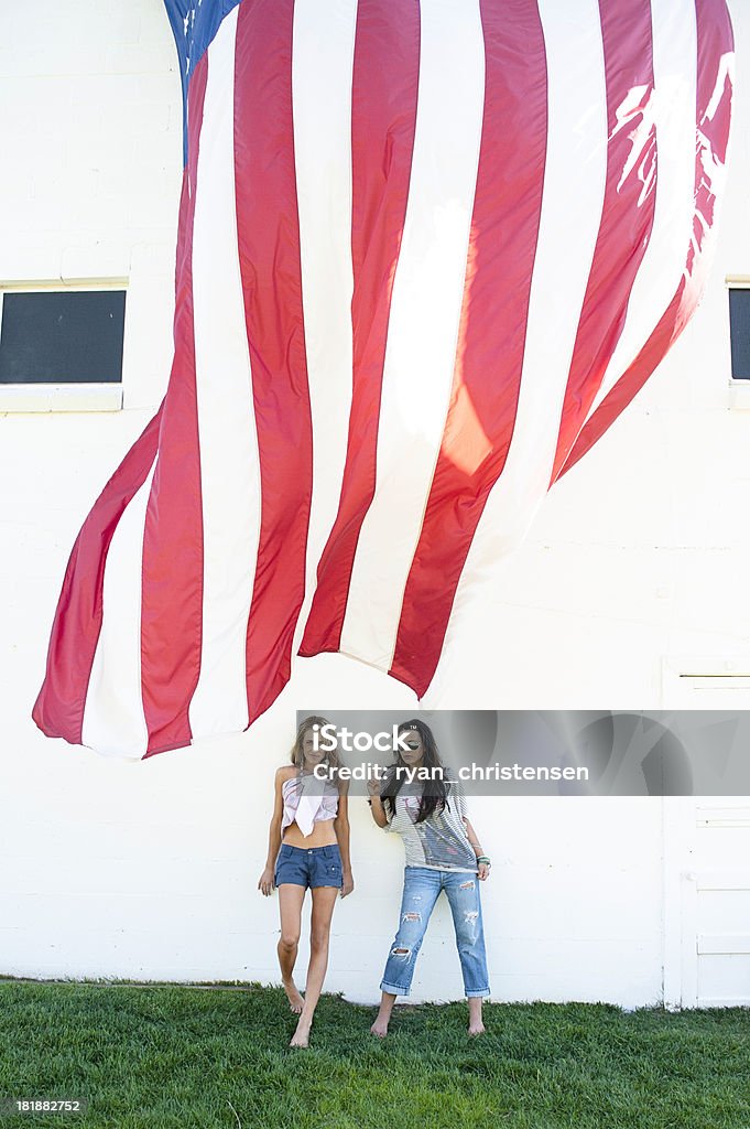 Belle jeune femme debout par un drapeau américain contre un mur - Photo de 4 juillet libre de droits