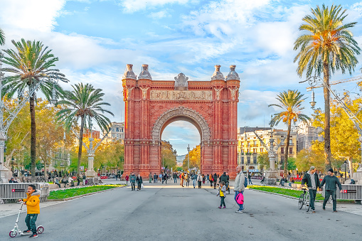 Barcelona, Spain - November 26, 2021: Many people walk along Passeig de Lluis Companys street near the Arc de Triomphe in Barcelona on a sunny autumn day. Bright colorful cityscape