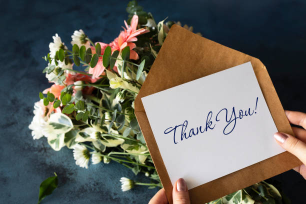 Thank you card in hands, message, envelope, flowers bouquet