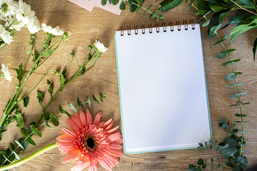 Top view flat lay empty note book with summer leaves and daisy flowers mockup.