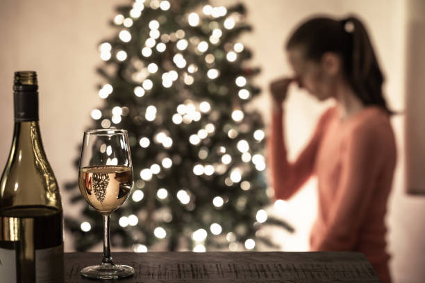 Sad, tired woman sitting next to Christmas tree.