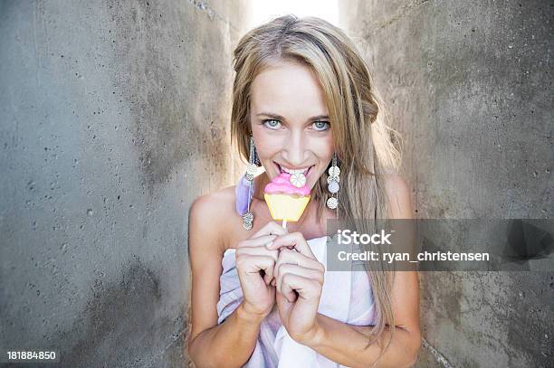 Photo libre de droit de Belle Jeune Femme De Ciment Murs Mâcher Un Cupcake Sucker banque d'images et plus d'images libres de droit de A la mode