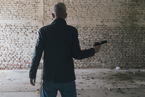 Criminal man holding handgun. Actor performance, not real crime, gun is replica.