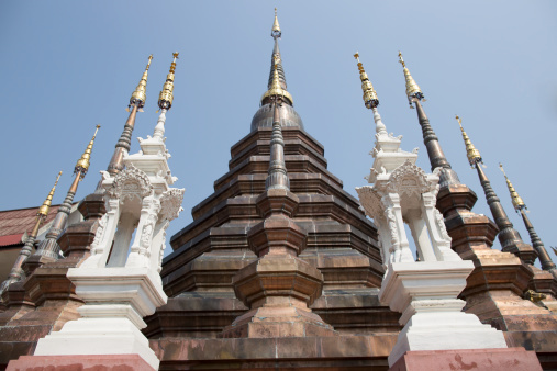 Impressive bronze stupa at the Buddhist temple Wat Phan Tao in Chiang Mai, Thailand. In front of this, there are two porcelain carving in white color.