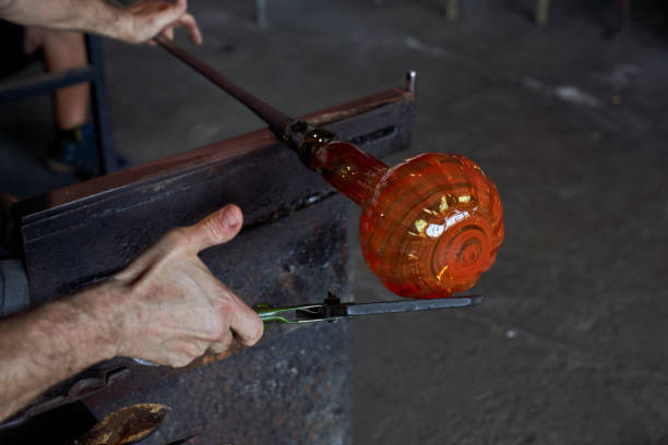 istock Crop gaffer shaping melted glass in dark workroom 1818870498