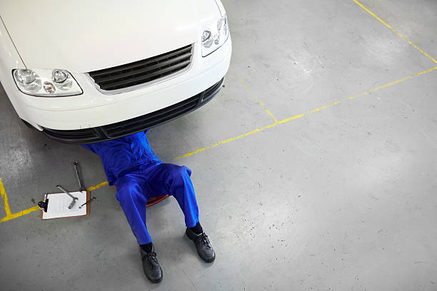 His autoshop has an impeccable reputation Top view of a mechanic on his back and working on the undercarriage of car - copyspace car mechanic top view stock pictures, royalty-free photos & images