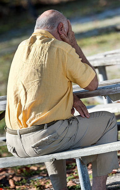 istock Rear view of senior man with head in hands outdoors at table 181888141