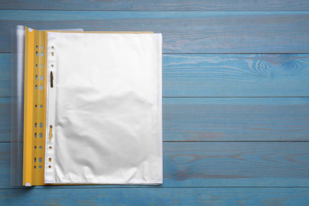 File folder with punched pockets on light blue wooden table, top view. Space for text
