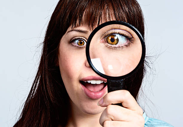 istock Smiling woman squints through magnifying glass 181890106