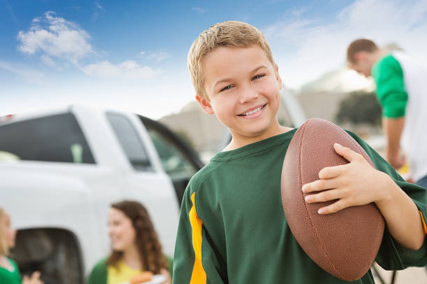 Young football fan at a tailgate party with his family Young football fan at a tailgate party with his family. people family tailgate party outdoors stock pictures, royalty-free photos & images
