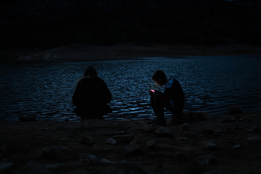 boy and girl sitting near the lake at the campsite in the evening, family vacation concept