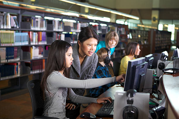 bibliothekar und studenten arbeiten am computer in der bibliothek - bibliothekar stock-fotos und bilder