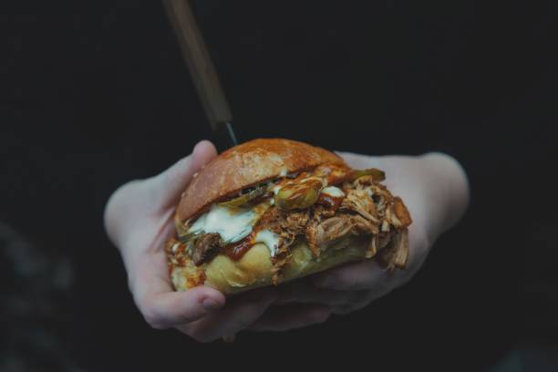 istock someone holding a sandwich that is very big and has shredded beef 1818908358