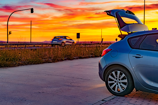 Labajos, Segovia, Spain. View of open car trunk against amazing sunset sky on a local road.