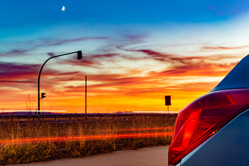 Labajos, Segovia, Spain. Car's rear taillight against a spectacular sunset sky on a country road.