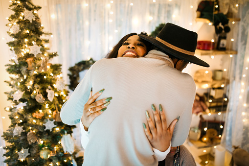 An African American man and woman give one another a hug on Christmas morning.