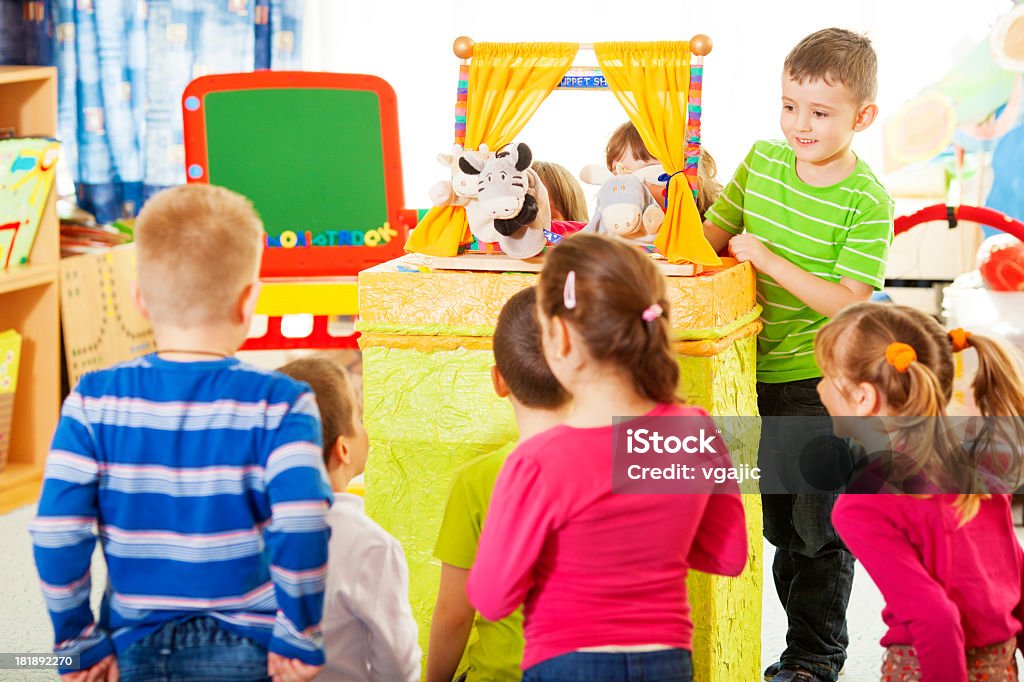 Children Playing Finger Puppet Show. Group of preschool children having craft activities at preschool, playing puppet show. Finger puppets, two children and teacher are audience. Selective focus to little boy making puppet show. Puppet Show Stock Photo