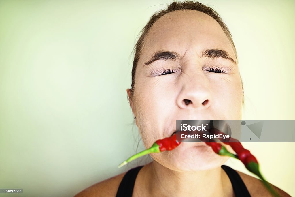 Ой-ой-ой! Гримасничать женщина, закуски на многие красный горячий chillis - Стоковые фото Перец чили роялти-фри