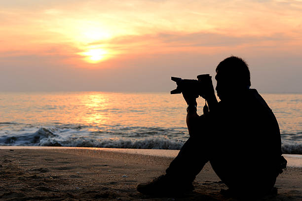 istock Silhouette photographer sitting on the beach 181893125