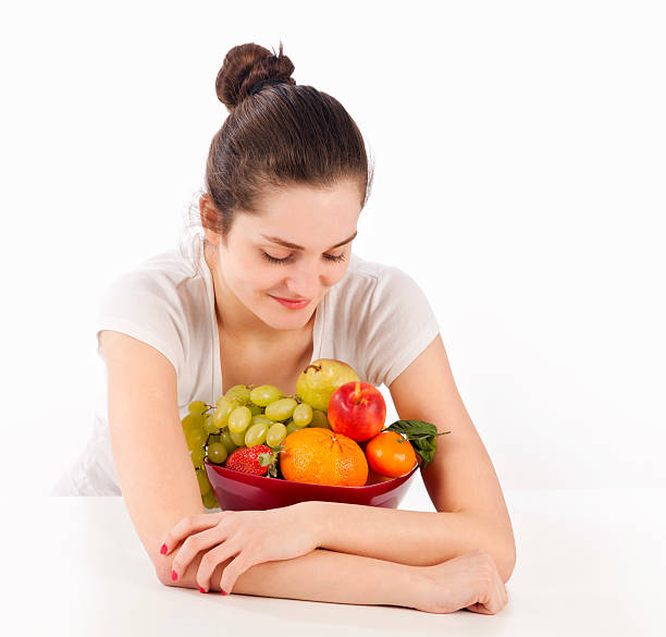 Woman and full bowl of fruits Young woman and full bowl of fruits on white background. Focus on foreground, shallow DOF. late teens isolated on white one person cute stock pictures, royalty-free photos & images