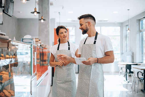 The photo showcases a collaborative scene in the bakery, featuring a male and a female worker working together to create delicious treats, capturing the essence of teamwork