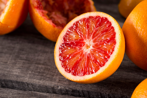 Half of a blood orange with other oranges in the background.