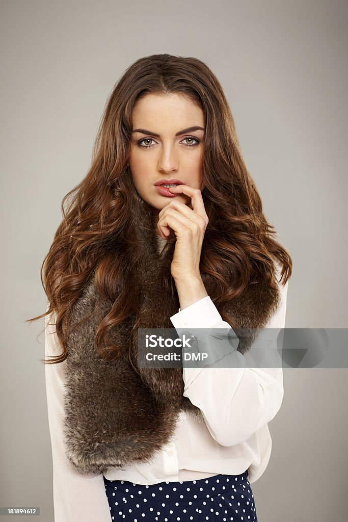 Pretty young woman biting fingernails Portrait of pretty young woman biting fingernails against grey background 20-24 Years Stock Photo