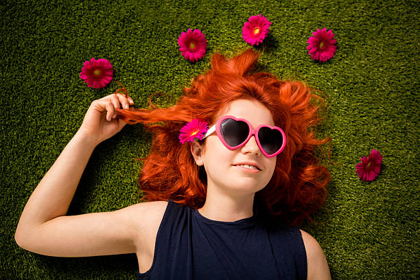 istock Redhaired girl with sunglasses lying in park on grass 181894679