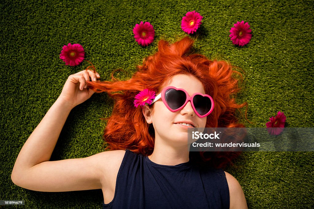 Redhaired garota com óculos de sol deitada na grama no parque - Foto de stock de Flor royalty-free