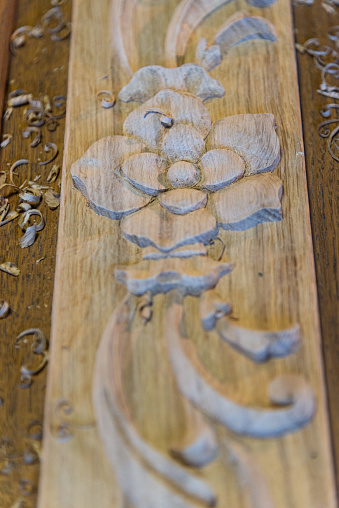 Close-up of a carved decoration on wood, with chisels, shallow depth of field in a workshop