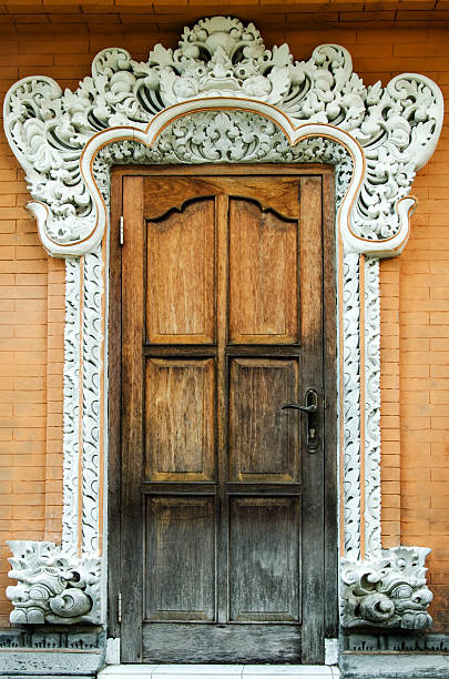 vintage door with some damage of the rainy season in a temple in Bali, Indonesia - with the typical decoration of the Hinduism.