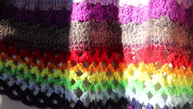 rug knitted from colored threads, fragment close-up in sunlight
