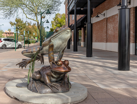 Mesa, AZ, USA, 11-27-23. Bronze frogs in front of historic building titled 