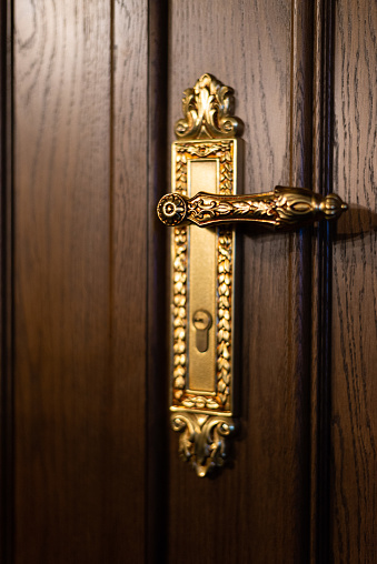 Antique interior golden doorknob on an old wooden door