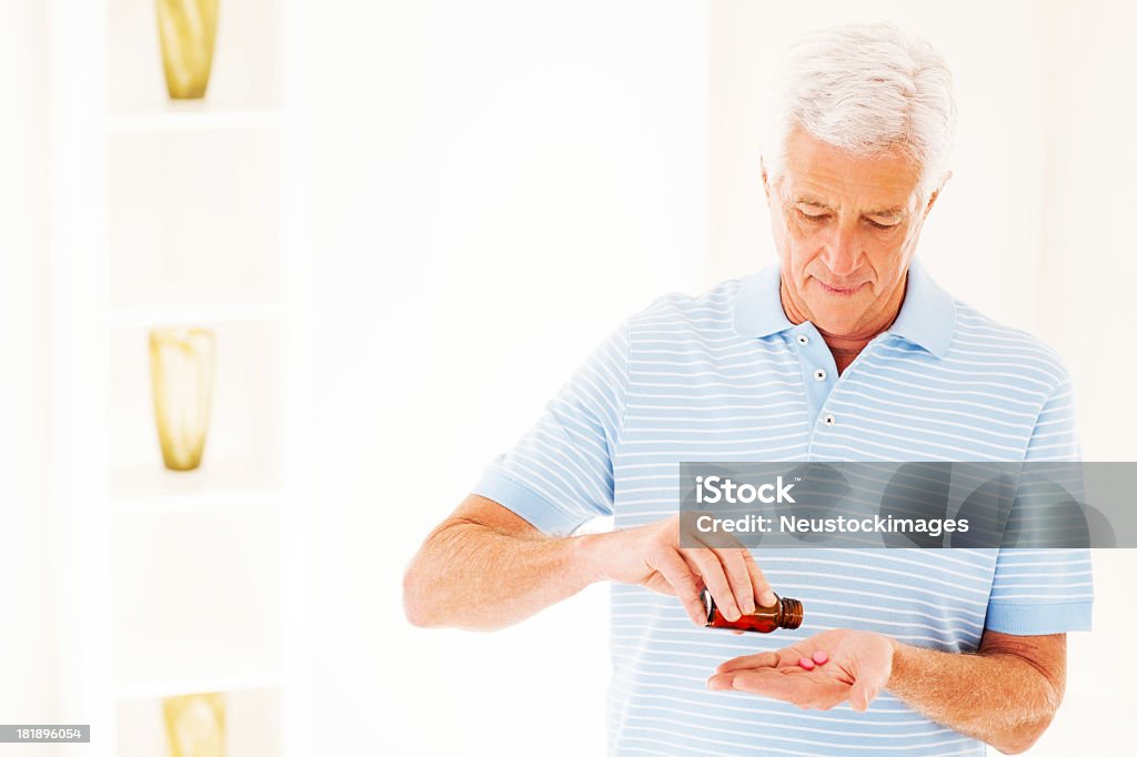 Uomo prendendo pillole di bottiglia di prescrizione - Foto stock royalty-free di 60-69 anni