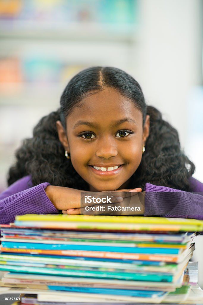 Elementary Student Elementary age girl posing on a stack of books. 10-11 Years Stock Photo