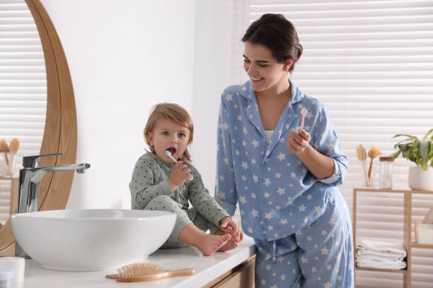 istock Mother and her daughter brushing teeth together in bathroom 1818962092