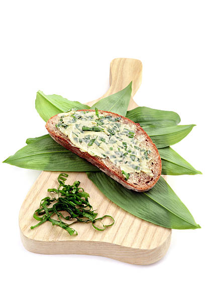 herb butter wild garlic (Allium ursinum) on slice of bread herb butter wild garlic (Allium ursinum) on slice of bread at wooden cutting board. white isolated background zigeunerlauch stock pictures, royalty-free photos & images