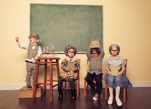 A group of kids dressed up as senior citizens have fun with a game of Bingo.