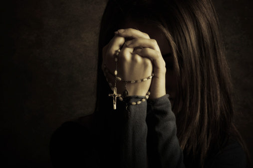 Catholic girl praying with rosary
