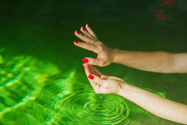 istock hands with red nail polish in hot water pool 1818980640