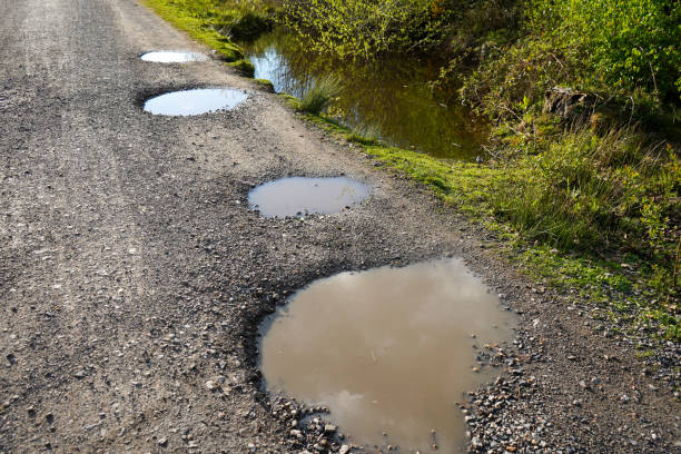 istock Puddles and potholes on a single track road 1818983230