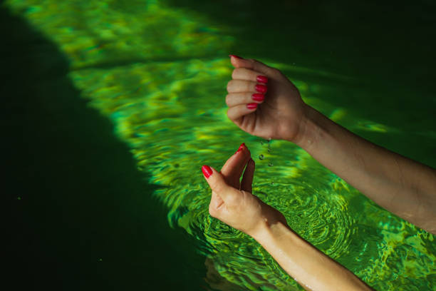 istock hands with red nail polish in hot water pool 1818984147