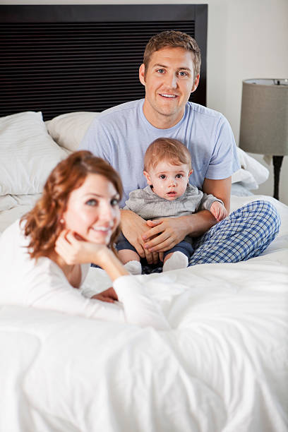 Young family with baby in bedroom Young couple (20s) with baby boy (8 months) relaxing on bed.  Focus on father and baby. Sc0601 stock pictures, royalty-free photos & images