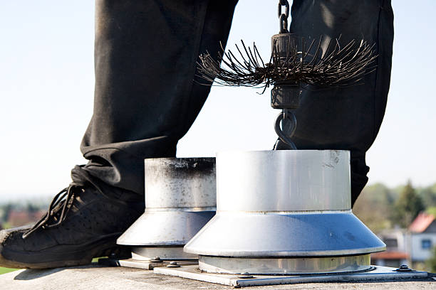 close up of a chimney sweep on the roof Close up of a chimney sweep on top of the chimney. Wearing the traditional workwear and holding a rope with the broom inside of the chimney. Clear sky in the background. chimney stock pictures, royalty-free photos & images